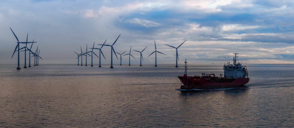 Vessel sailing infront of a wind farm.
